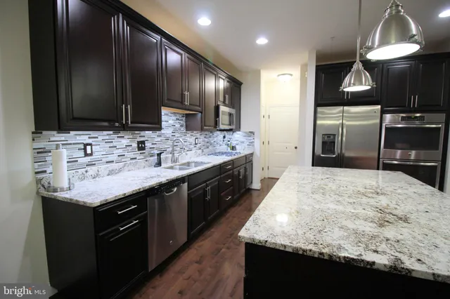 a kitchen with stainless steel appliances granite countertop wooden cabinets a sink dishwasher a stove and a refrigerator