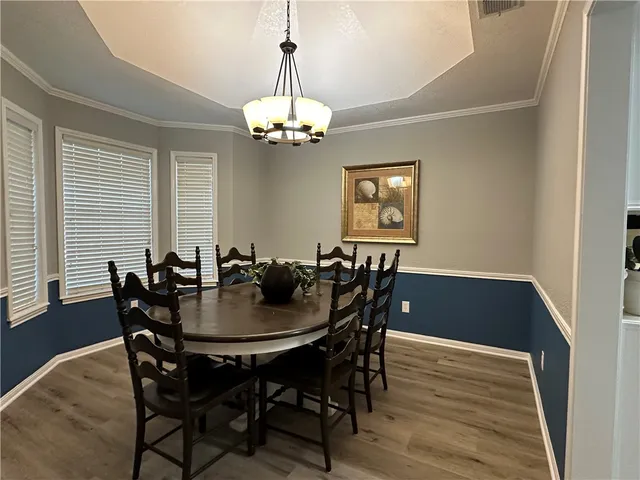a view of a dining room with furniture a chandelier and wooden floor