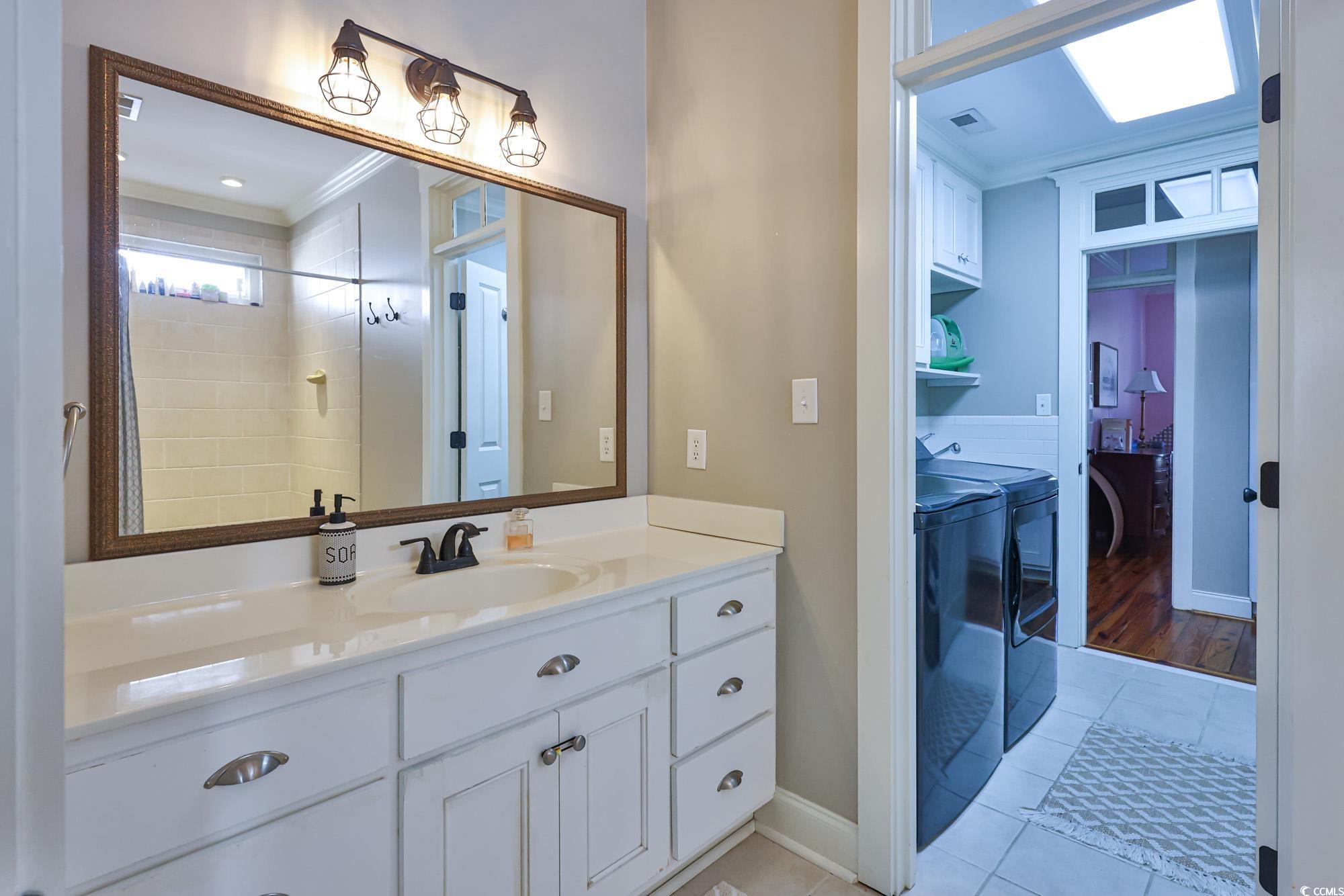 998 Shipmaster Avenue Myrtle Beach, SC 29579 - Photo 11 of 40 Full bath with separate washer and dryer, vanity, light tile patterned flooring, crown molding, and tiled shower