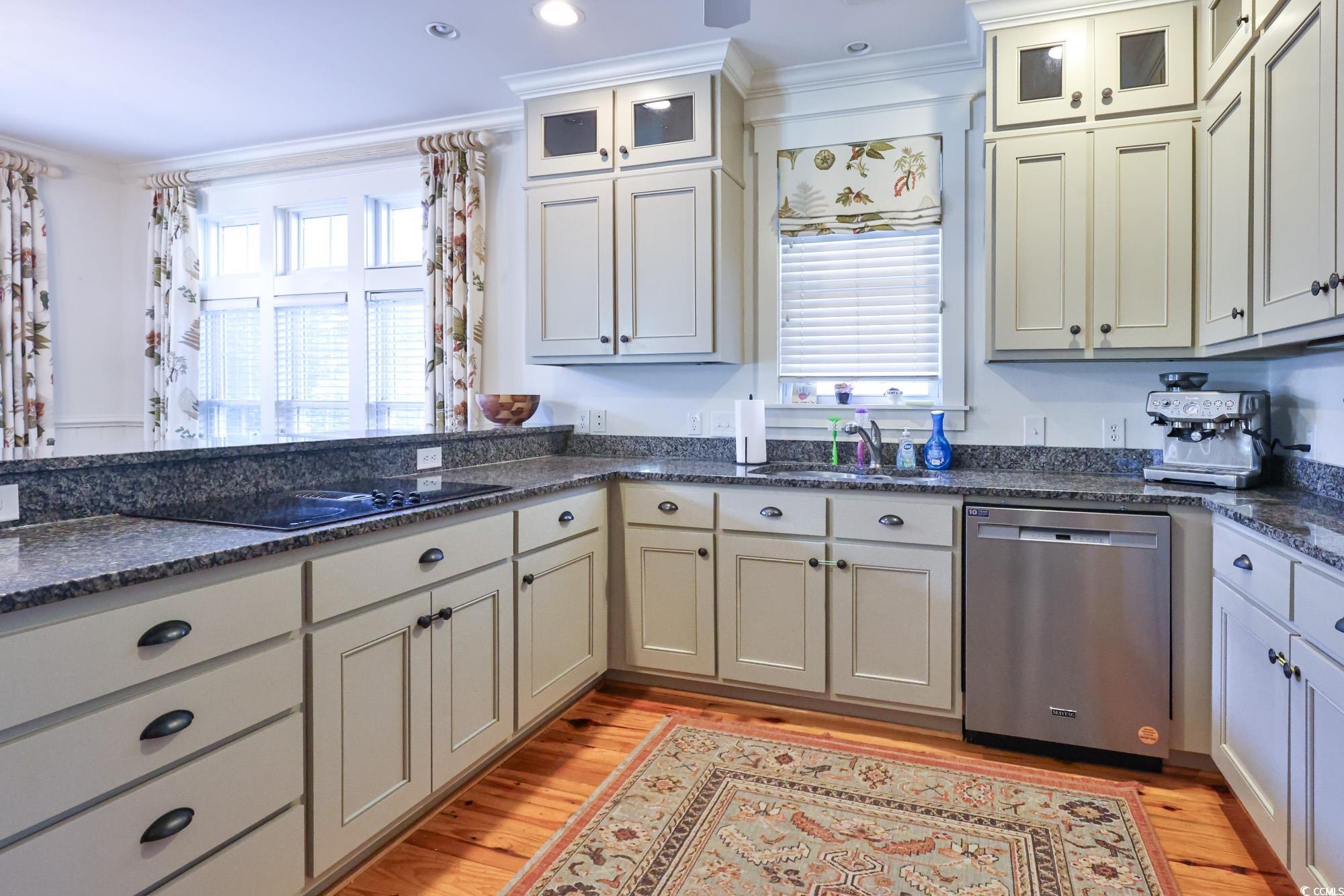 998 Shipmaster Avenue Myrtle Beach, SC 29579 - Photo 14 of 40 Kitchen with crown molding, stainless steel dishwasher, light wood-style floors, glass insert cabinets, and dark stone counters