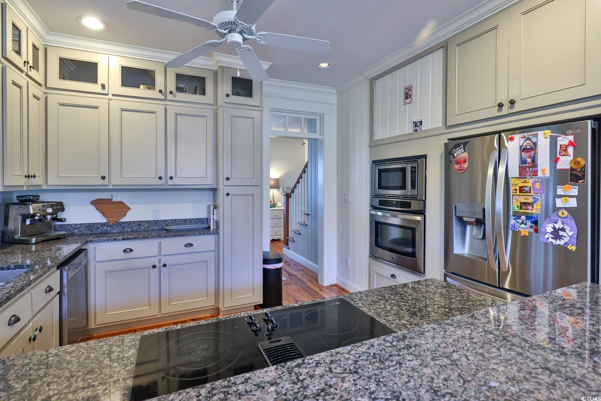 998 Shipmaster Avenue Myrtle Beach, SC 29579 - Photo 16 of 40 Kitchen with stainless steel appliances, dark stone counters, ornamental molding, ceiling fan, and light wood-style flooring