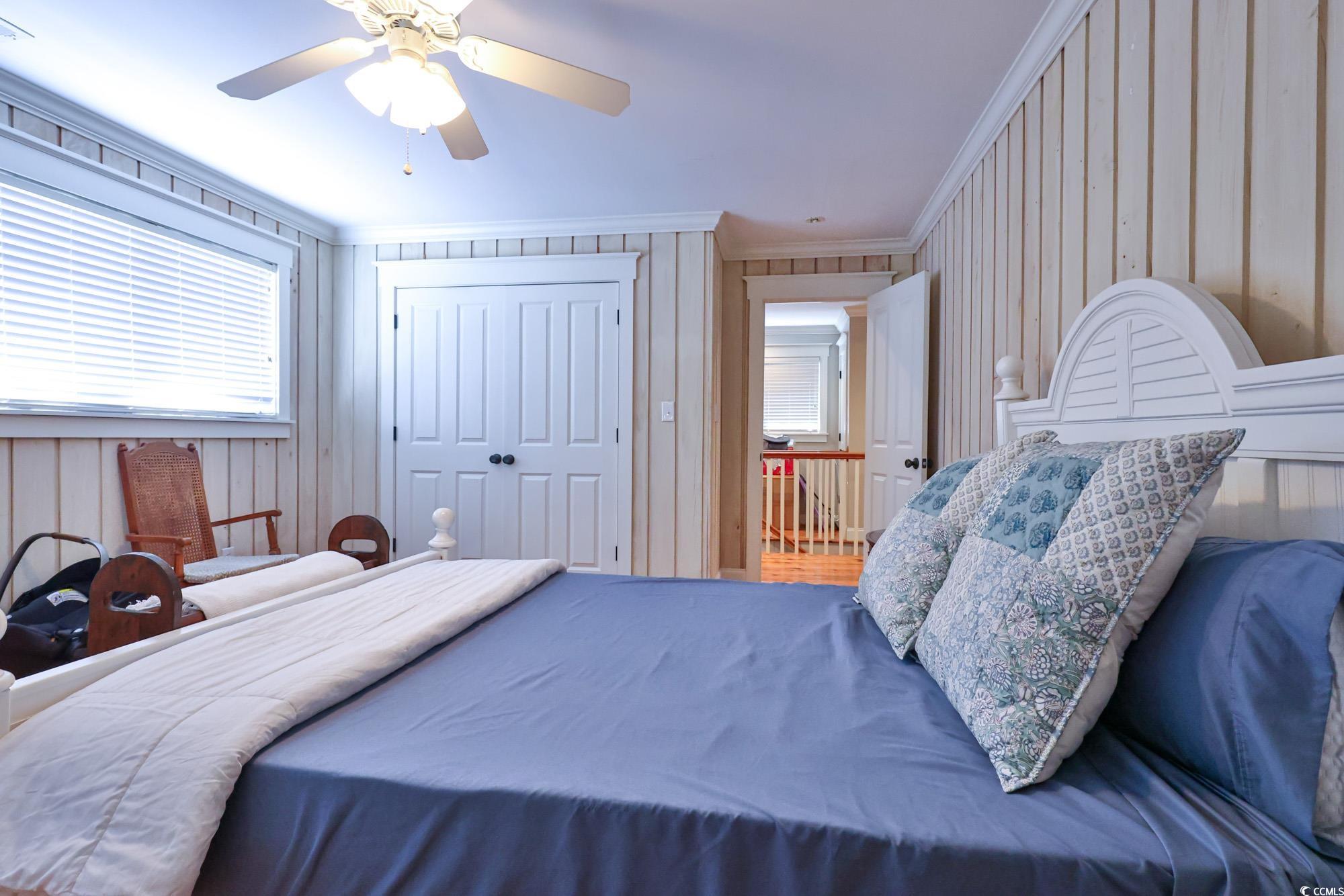 998 Shipmaster Avenue Myrtle Beach, SC 29579 - Photo 24 of 40 Bedroom featuring crown molding, a ceiling fan, a closet, multiple windows, and wooden walls