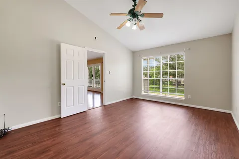 a view of an empty room with a window and wooden floor