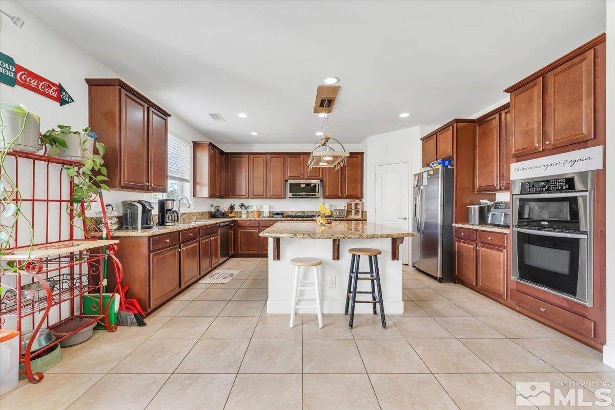 10050 Barrel Racer Drive Reno, NV 89521 - Photo 12 of 30 a kitchen with stainless steel appliances granite countertop a refrigerator and a stove top oven