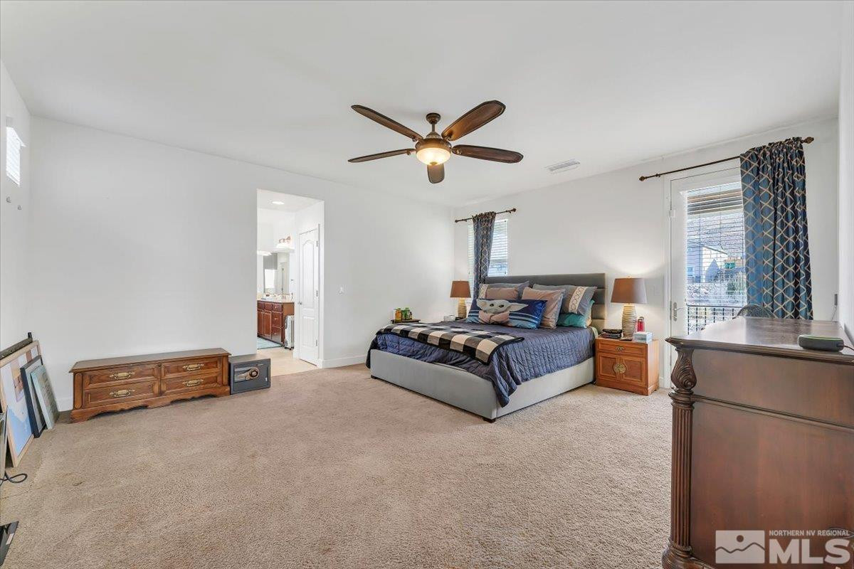 10050 Barrel Racer Drive Reno, NV 89521 - Photo 18 of 30 a spacious bedroom with a bed a window and a chandelier