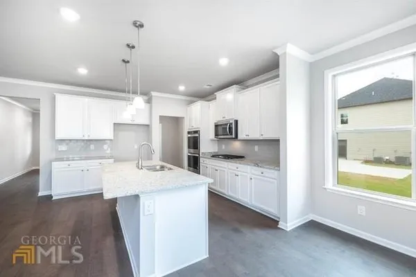 a large kitchen with kitchen island a sink a stove a center island and wooden floor