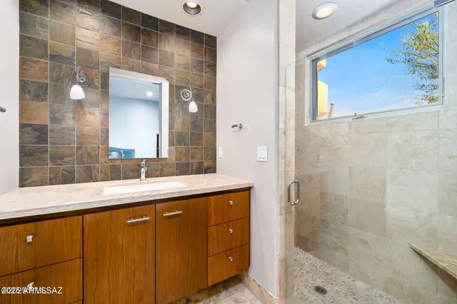 a bathroom with a granite countertop sink a mirror and shower