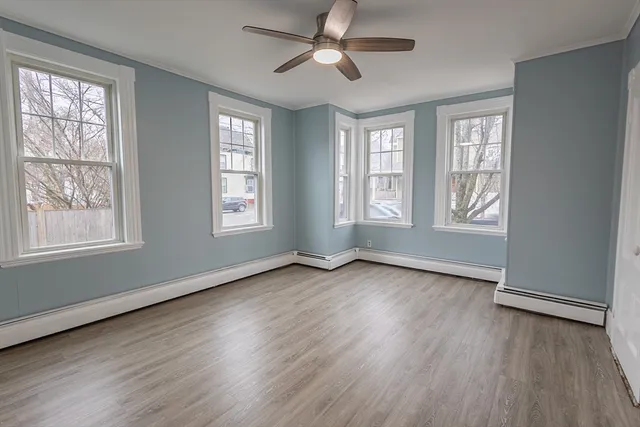 a view of an empty room with wooden floor and window