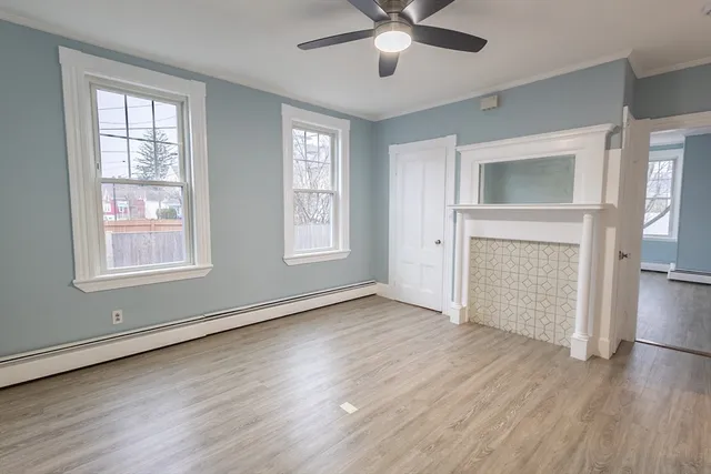 an empty room with wooden floor a ceiling fan and windows
