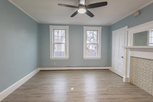 a view of empty room with wooden floor and fan