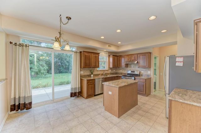 a kitchen with stainless steel appliances granite countertop a sink stove refrigerator and cabinets