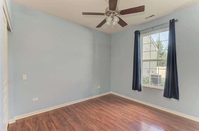 an empty room with wooden floor closet and windows