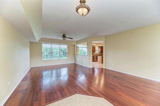 an empty room with wooden floor cabinet and windows