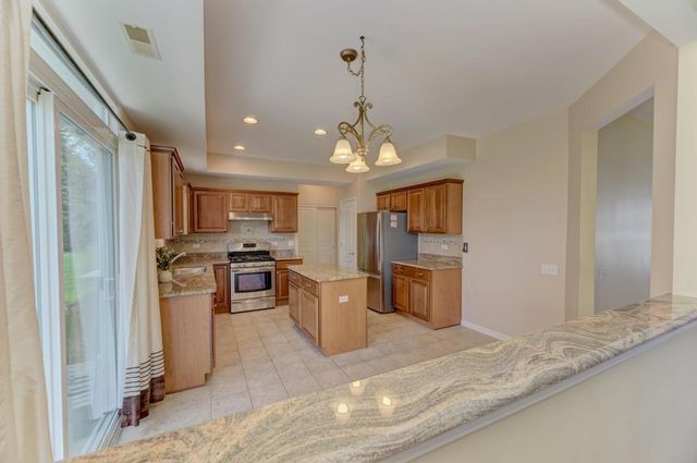 a kitchen with kitchen island a counter top space a sink stainless steel appliances and cabinets