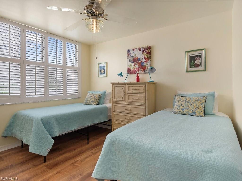 5550 Heron Point Drive, Unit 105 Naples, FL 34108 - Photo 12 of 20 a bedroom with two beds and a chandelier