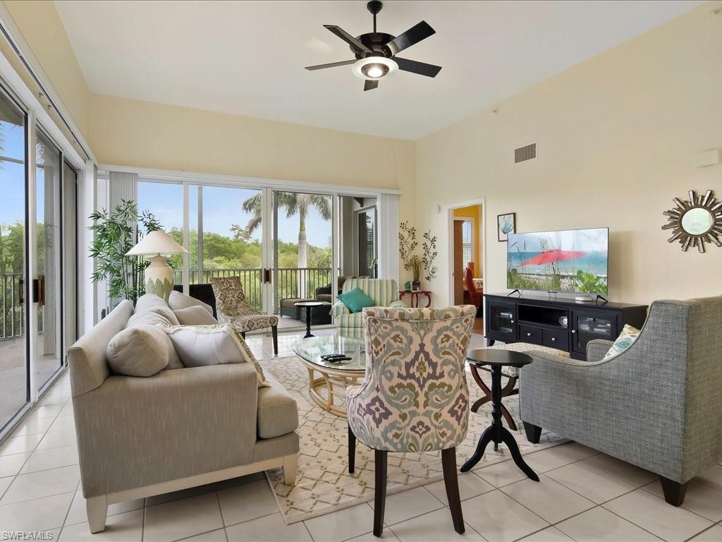 5550 Heron Point Drive, Unit 105 Naples, FL 34108 - Photo 2 of 20 a living room with furniture a floor to ceiling window and a flat screen tv