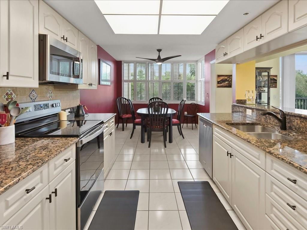 5550 Heron Point Drive, Unit 105 Naples, FL 34108 - Photo 6 of 20 a kitchen with stainless steel appliances granite countertop sink stove and cabinets