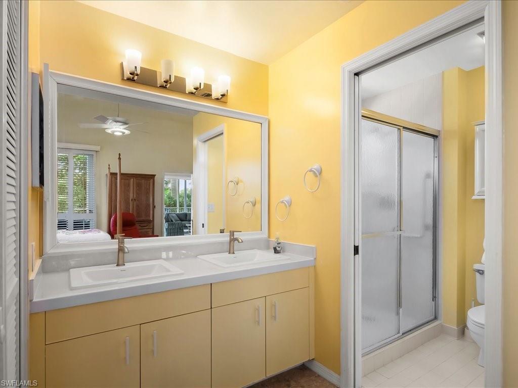 5550 Heron Point Drive, Unit 105 Naples, FL 34108 - Photo 10 of 20 a bathroom with a double vanity sink and mirror