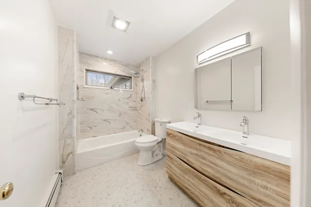 a spacious bathroom with a bathtub shower sink mirror and toilet