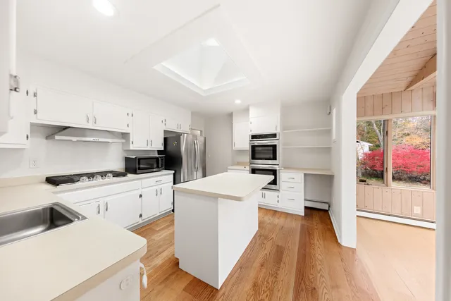 a kitchen with stainless steel appliances kitchen island wooden floors and white cabinets