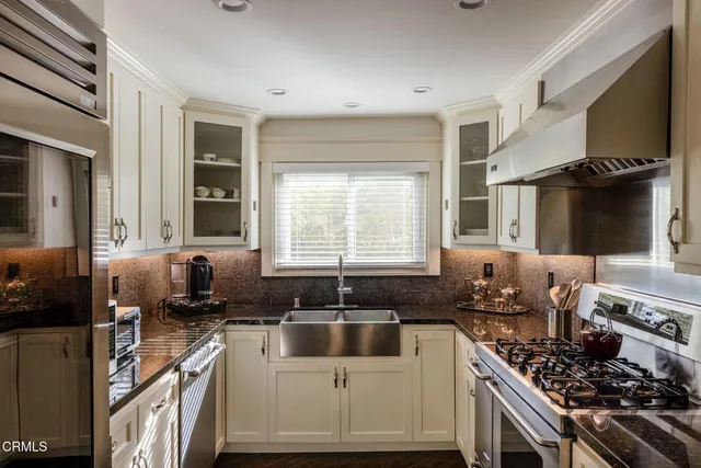 a kitchen with granite countertop a sink stainless steel appliances and cabinets