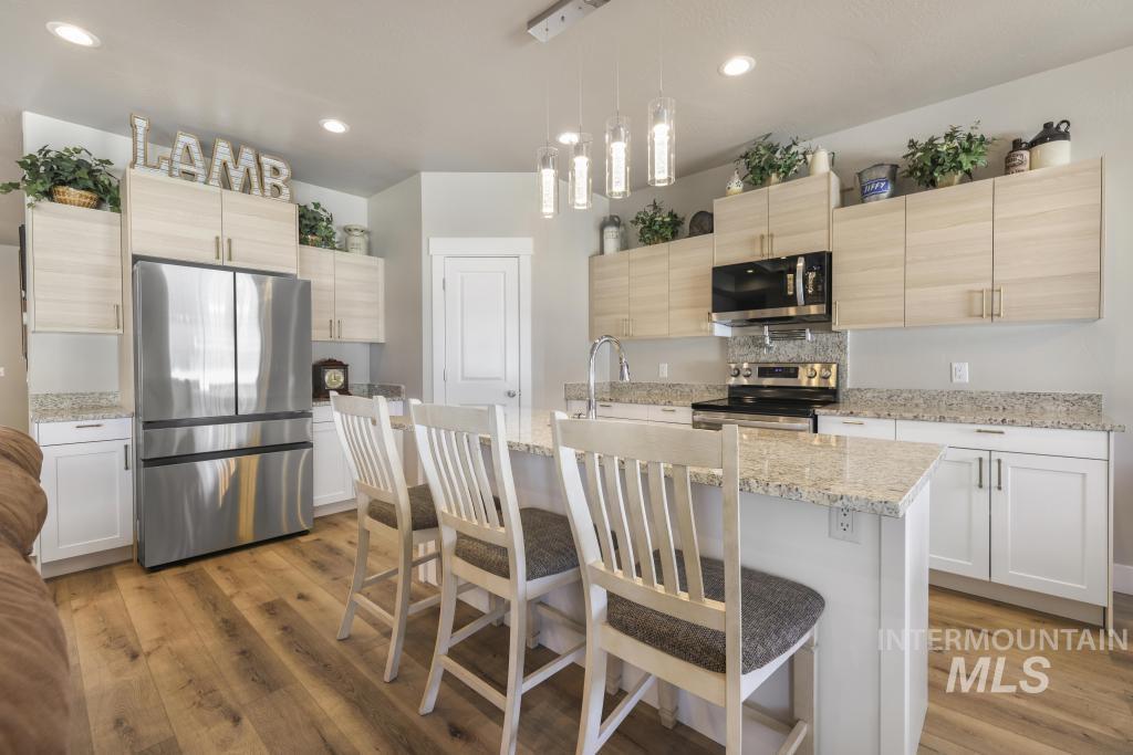1020 13th Street Rupert, ID 83350 - Photo 11 of 30 Kitchen with stainless steel appliances, decorative light fixtures, light stone countertops, light wood finish cabinetry, and a kitchen island with sink