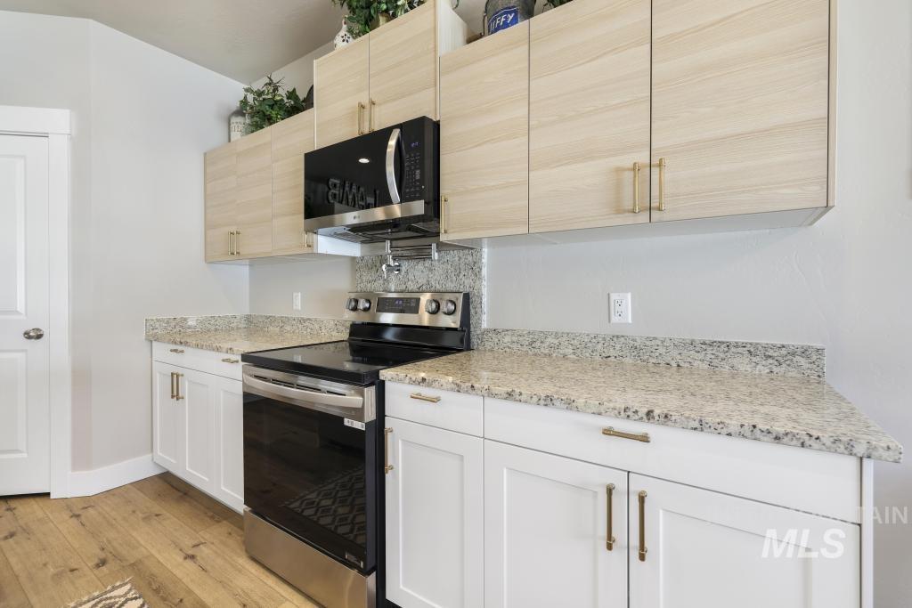 1020 13th Street Rupert, ID 83350 - Photo 14 of 30 Kitchen with stainless steel appliances, light stone counters, light wood-style floors, backsplash, and light wood finish cabinets