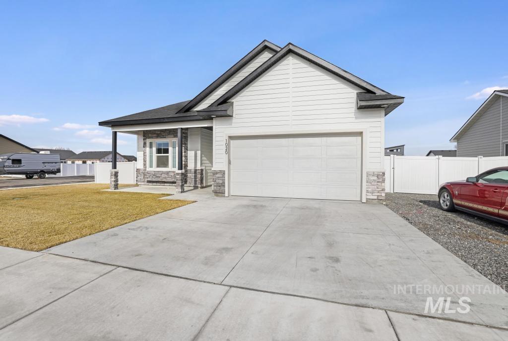 1020 13th Street Rupert, ID 83350 - Photo 2 of 30 View of front of house featuring stone siding, a porch, concrete driveway, and an attached garage