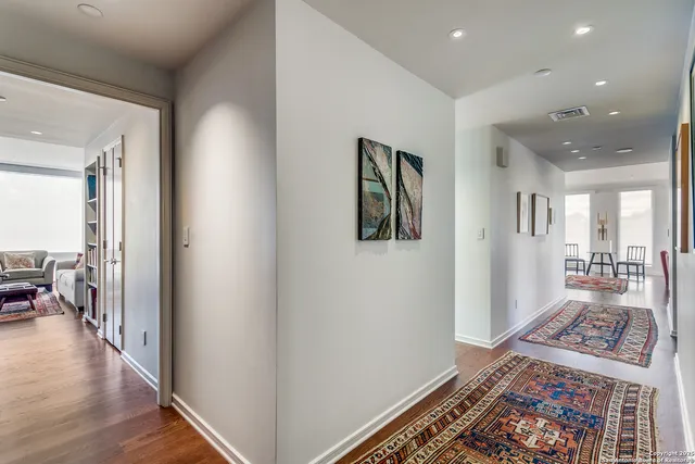 a view of a hallway with wooden floor and a rug