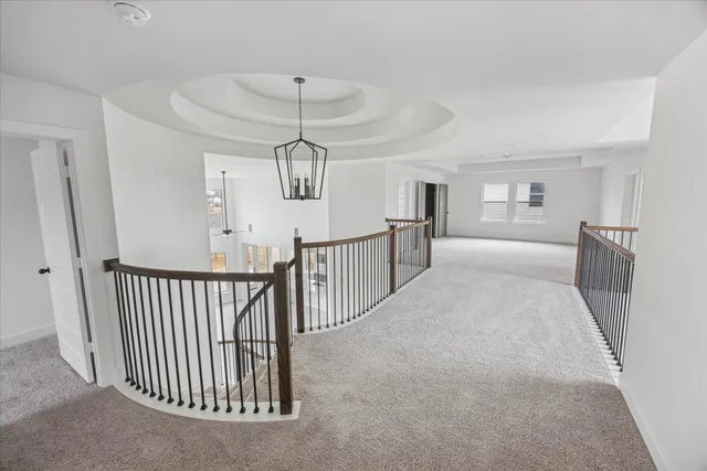 an empty room with staircase and a chandelier fan