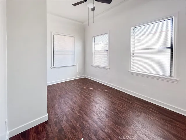 an empty room with wooden floor chandelier fan and windows