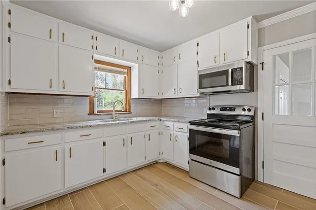 a kitchen with granite countertop white cabinets stainless steel appliances and a sink