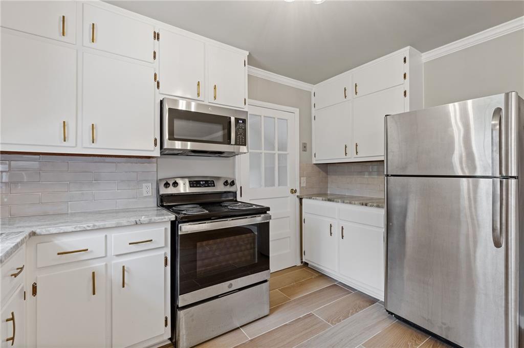 1312 Milstead Avenue Conyers, GA 30012 - Photo 12 of 34 a kitchen with granite countertop white cabinets and stainless steel appliances