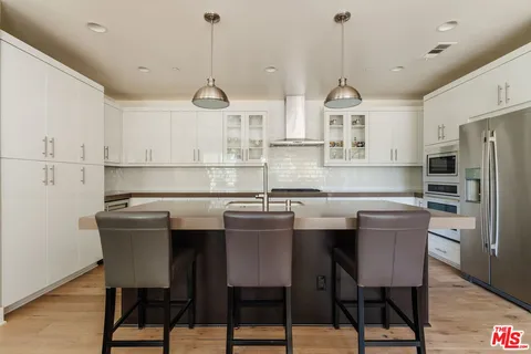 a kitchen with stainless steel appliances a dining table chairs and white cabinets