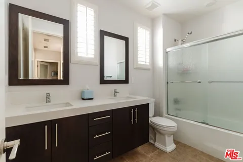 a bathroom with a toilet sink double vanity and mirror