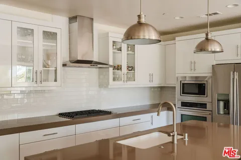 a kitchen with granite countertop a stove a sink and a refrigerator