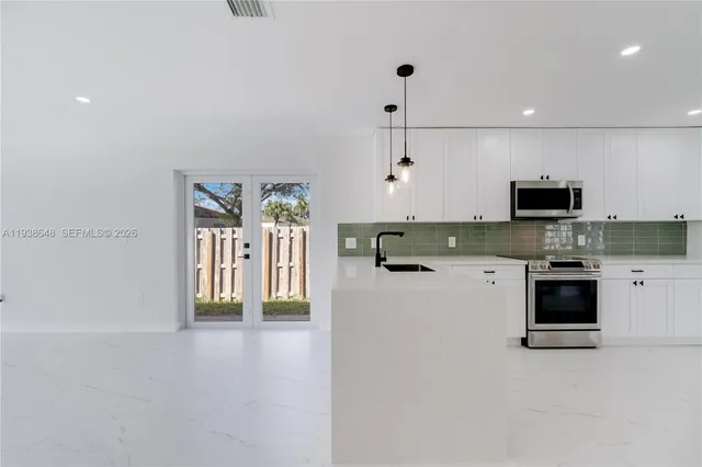a kitchen with stainless steel appliances granite countertop a stove a sink and a refrigerator