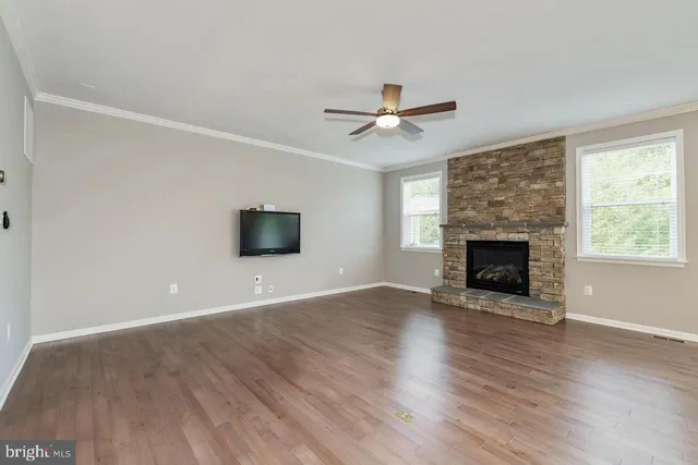 an empty room with wooden floor fireplace and windows