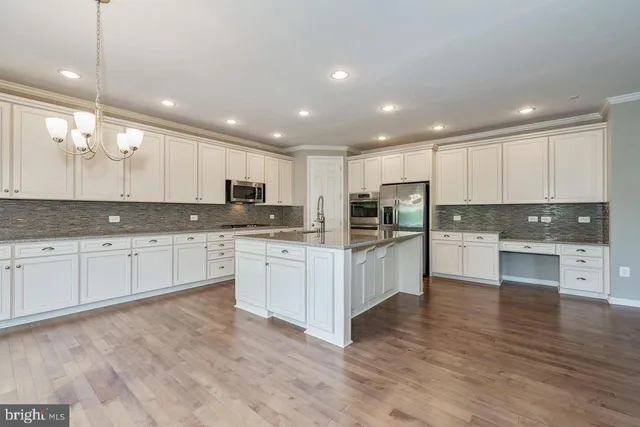 a large kitchen with granite countertop a large counter top stainless steel appliances and cabinets