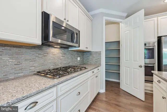 a kitchen with stainless steel appliances granite countertop a stove a microwave and a white cabinets