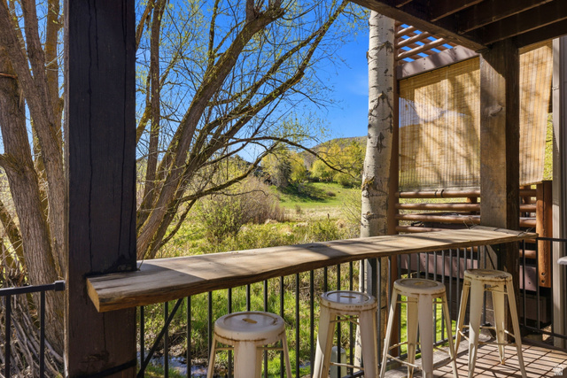 7935 Mustang Loop Road Park City, UT 84098 - Photo 25 of 60 Outdoor bar area featuring a live-edge wooden countertop, natural wood support beams, and a slatted wood trellis overhead