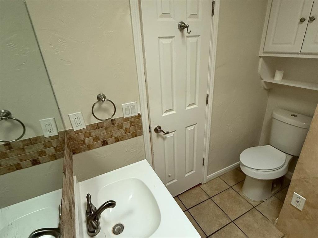 6505 Mc Cormick Ranch Court Plano, TX 75023 - Photo 20 of 21 Bathroom featuring a single vanity with a white basin sink, brushed nickel faucet, and a mosaic tile backsplash