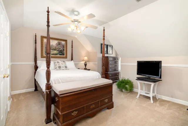 a bedroom with a bed a flat screen tv and a chandelier
