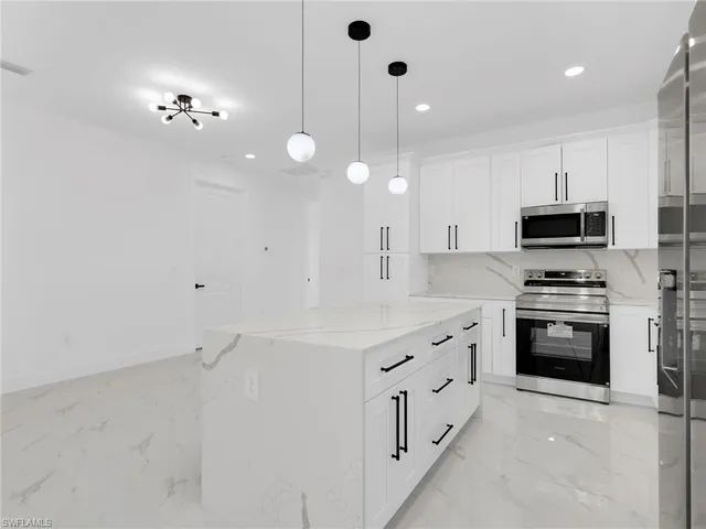 a kitchen with granite countertop white cabinets and stainless steel appliances
