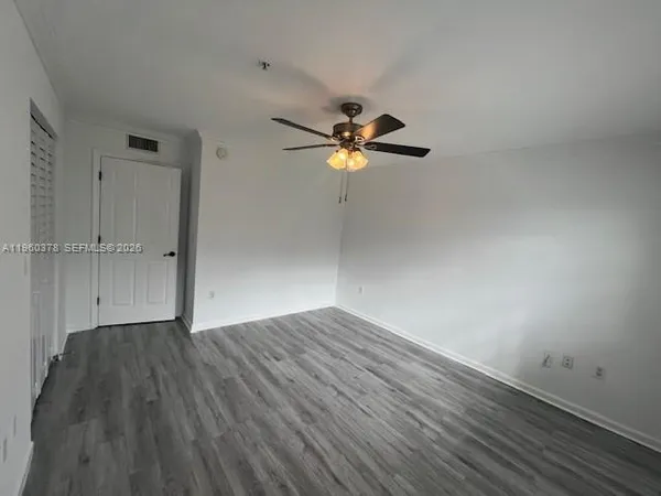 an empty room with wooden floor and a ceiling fan