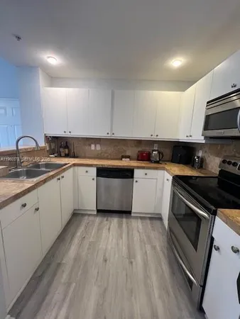 a kitchen with sink a microwave and cabinets