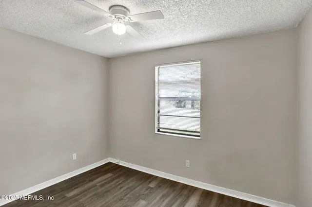 an empty room with a window and a fan