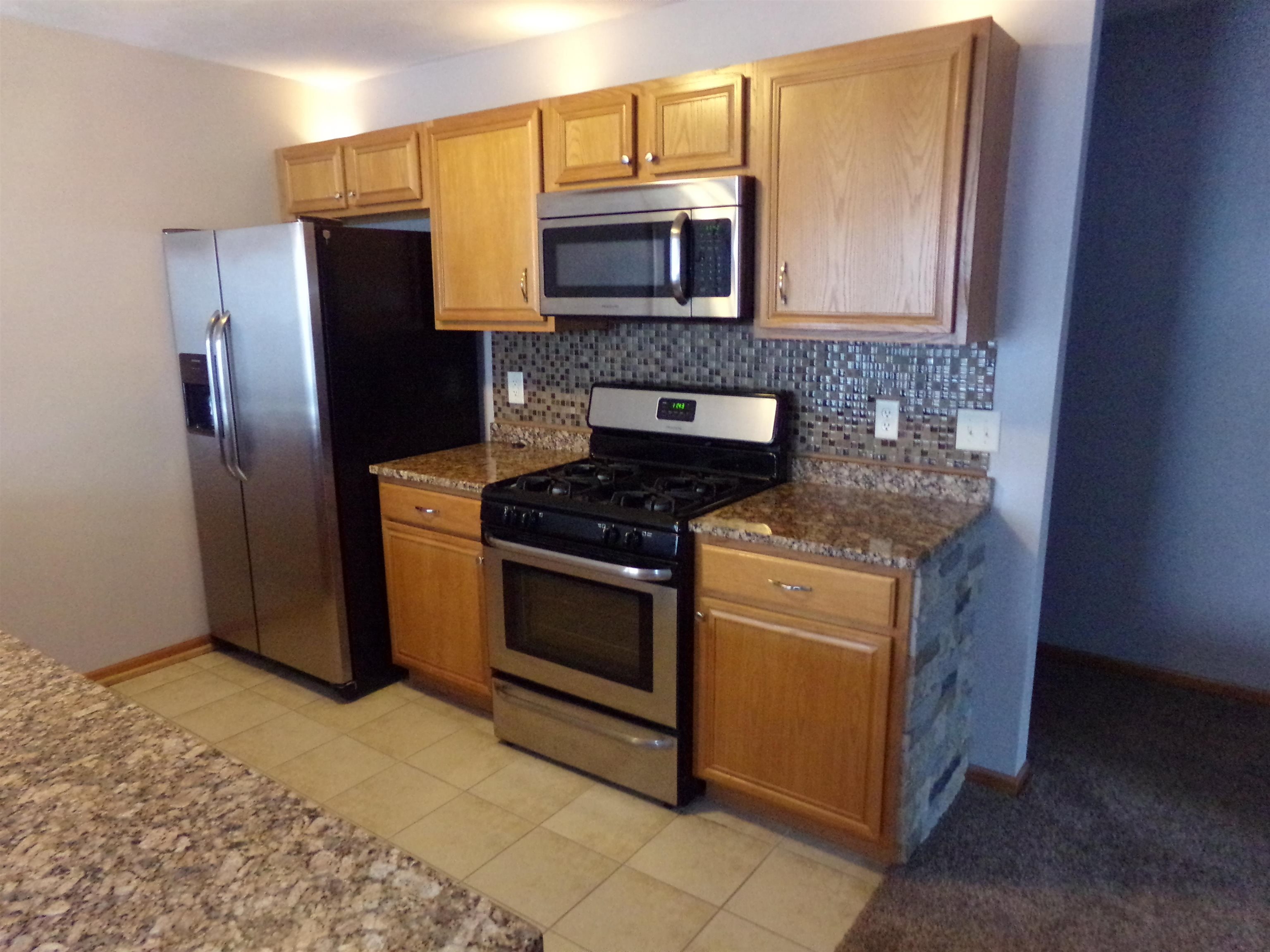 10164 Monarch Road Roscoe, IL 61073 - Photo 3 of 11 a kitchen with stainless steel appliances granite countertop a stove a refrigerator and a microwave