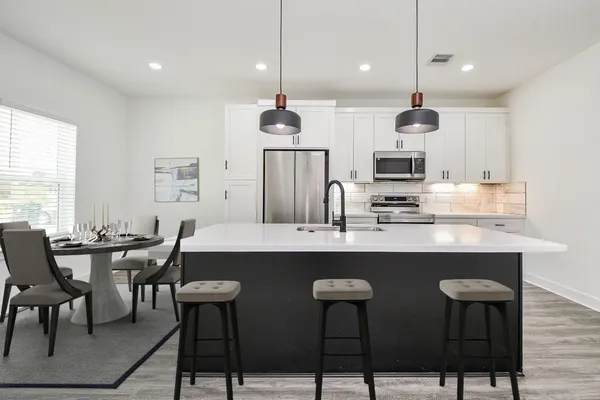 a kitchen with stainless steel appliances kitchen island granite countertop a table chairs sink and microwave
