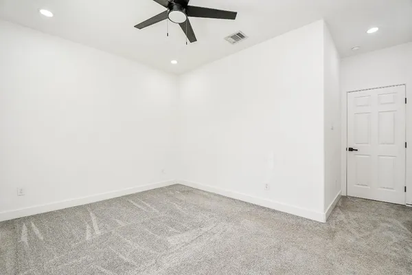 an empty room with a ceiling fan and window